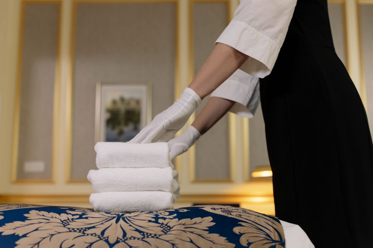 heros-img A hotel housekeeper carefully arranges clean towels in a luxurious room setting.